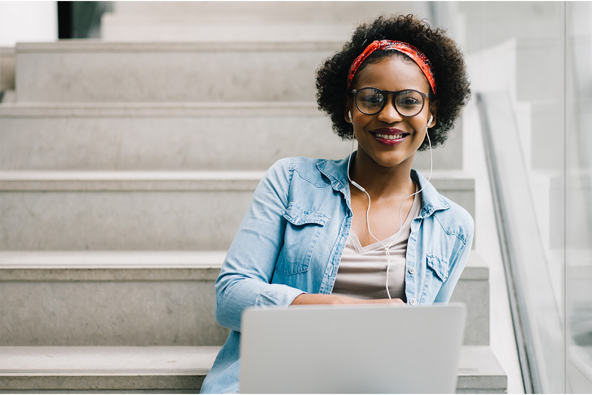 woman on laptop sitting on stairs smiling